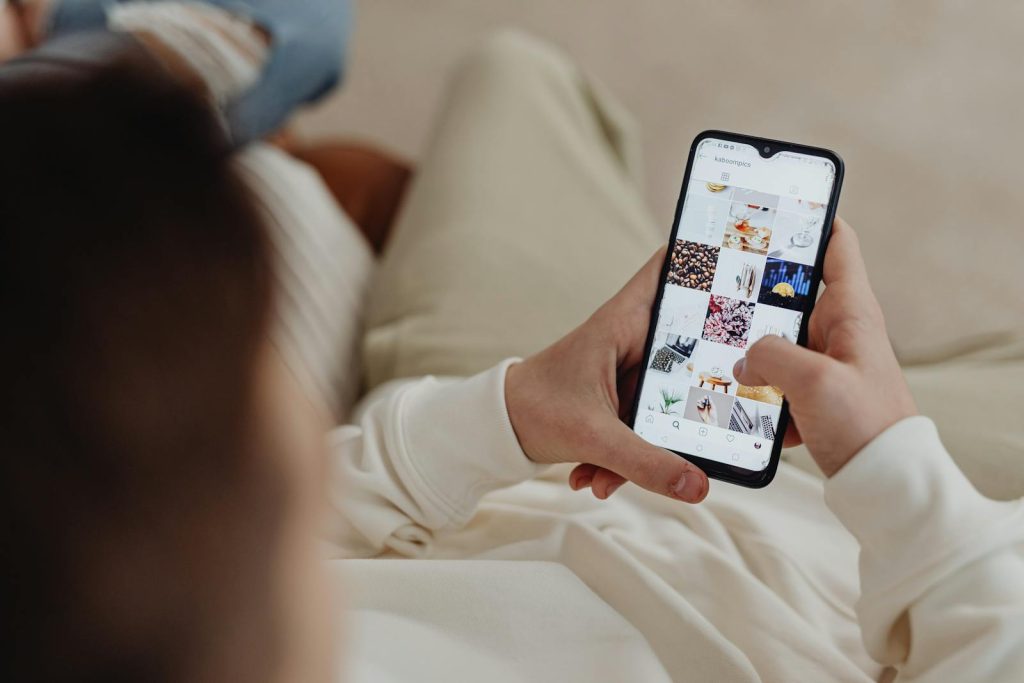 Person using smartphone to browse Instagram indoors, showing social media engagement.